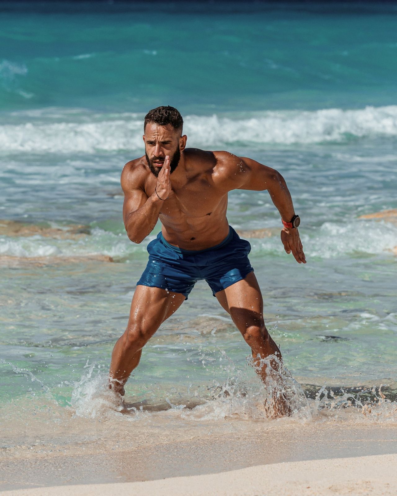 An athlete sprinting out of the sea onto the sand